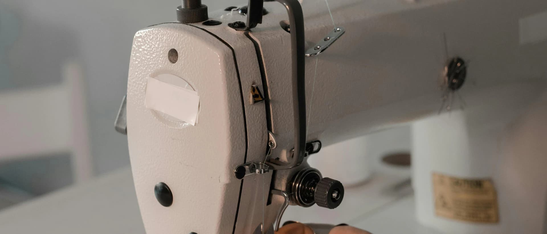 A tailor threading an industrial sewing machine on the workshop floor